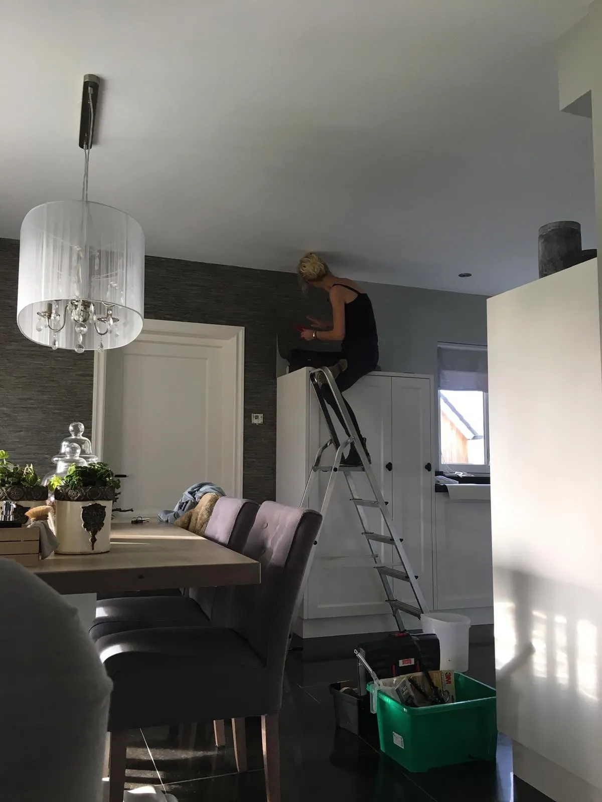 Karin aan het werk met een baan behang tegen de muur